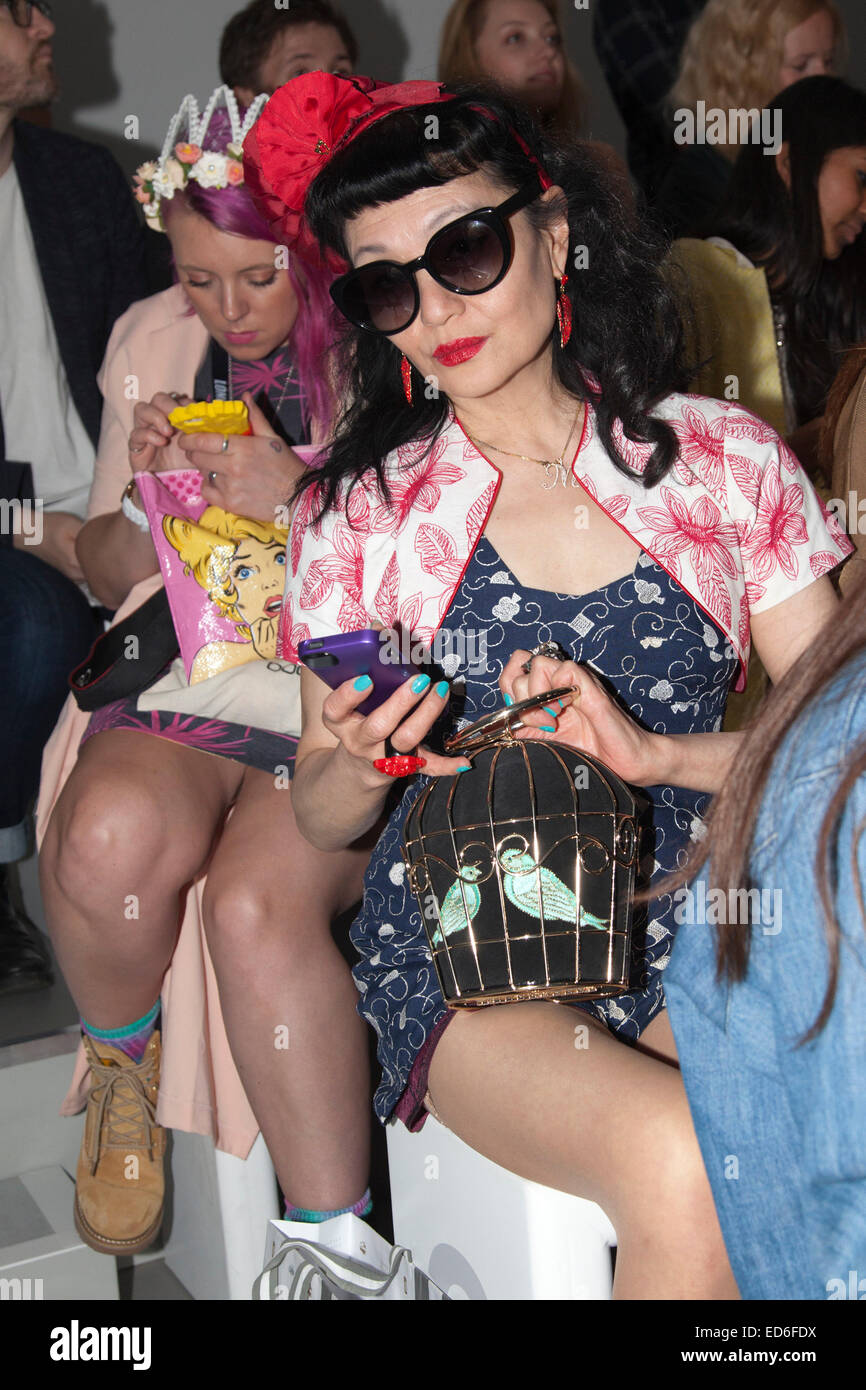 Besucher auf dem Handy vor einer Modenschau tragen schrulligen Mode, London Fashion Week Stockfoto