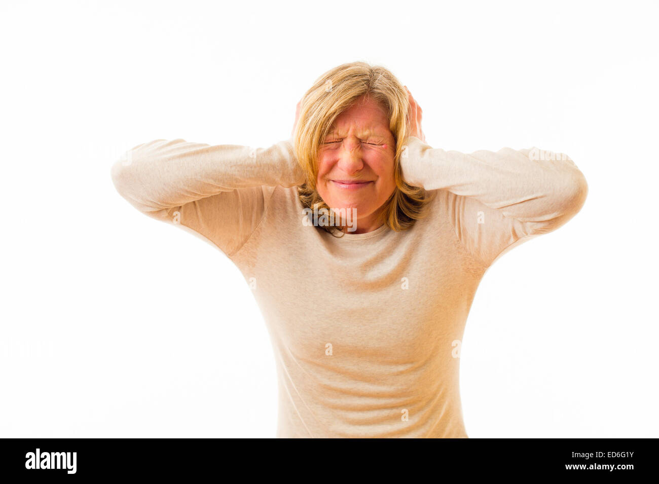 Eine vierzig Jahre alten kaukasischen Frau für ihre Ohren mit den Händen blockieren laut Lärm in einer schmerzlich ohrenbetäubend lauten Umgebung vor einem weißen Hintergrund. UK Stockfoto