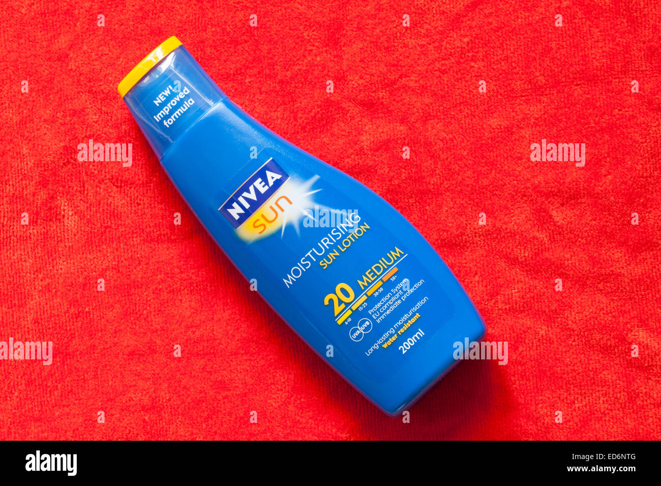 Flasche feuchtigkeitsspendende Sonnenlotion Nivea Sun Sonnencreme auf orangefarbenem Handtuch Nivea LSF 20 Stockfoto
