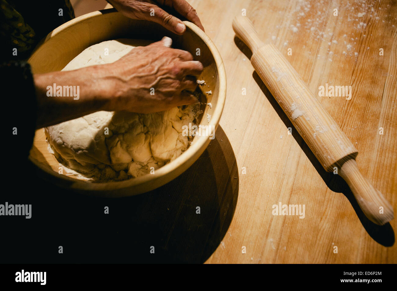Hände einer Frau, die Weizenbrotteig auf einem Holztisch knetet Stockfoto