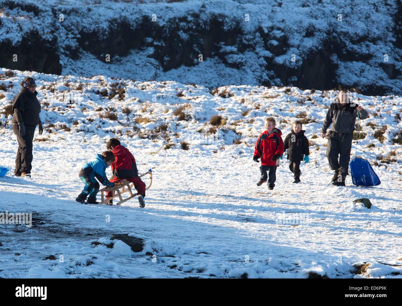 Kinder spielen auf Schlitten Rodel Spaß Schnee Ilkley moor Stockfoto