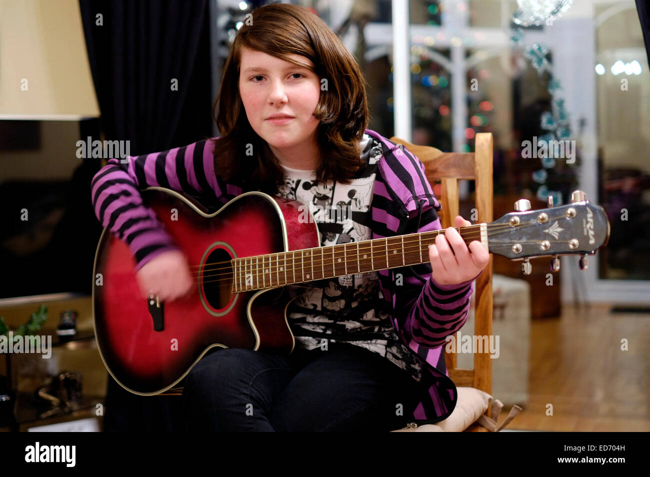 zwölf Jahre alte Mädchen spielt Gitarre für ihre Familie zur Weihnachtszeit Stockfoto