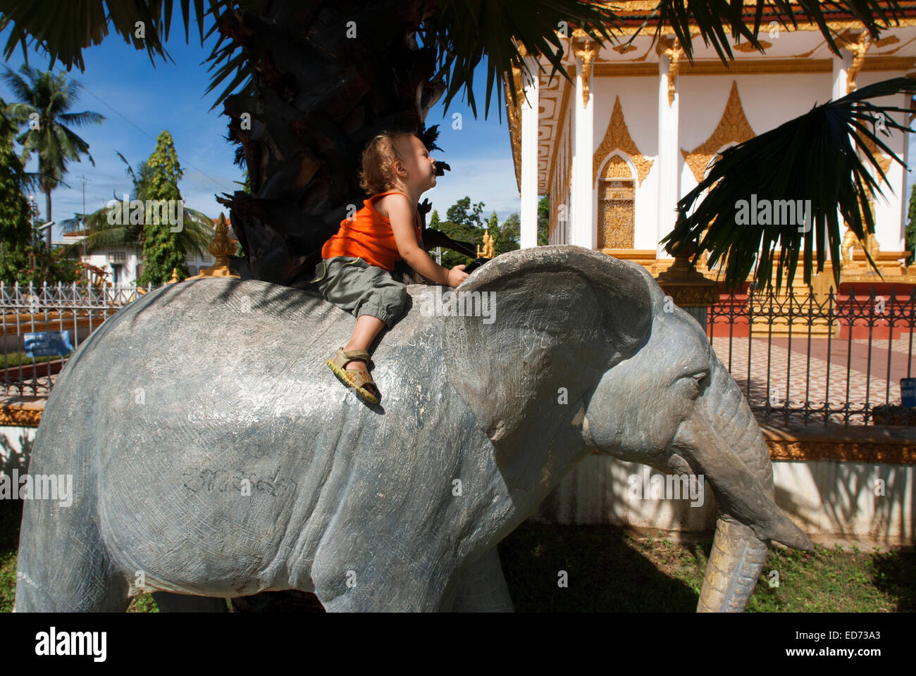 Mädchen hochgeladen eine Elefanten-Statue im Wat Kampheng Tempel. Battambang. Kambodscha. Reisen Sie mit Kinder. Wat Kampheng direkt hinter Stockfoto