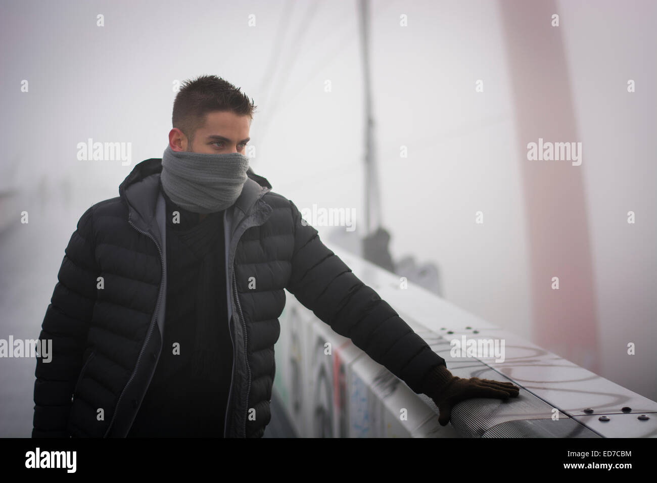 Junger Mann im Winter Mode stehen im Freien mit Schal versteckt sein Gesicht Stockfoto