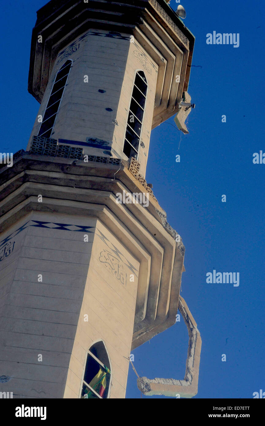 Kobane, Syrien. 21. Dezember 2014. Die kurdischen Verteidiger von Kobane nennen ihre Stadt "Stalingrad". Die Straßen sind Schutt gefüllt, zerbrochene Glas deckt den Boden überall und Scherben aus Metall und Schrapnell bedecken den Boden. Die meisten Häuser sind auf ihren Rahmen reduziert und nicht explodierte Bomben füllen die Straßen. In dieser zerstörten Stadt müssen die Überlebenden mit Handfeuerwaffen, Raketen, Sprengstoff und extrem heftigen alliierten Luftangriffen befassen. Über eine bewegen muss durchlaufen Löcher klopfte in Wänden zwischen Gebäuden oder unter Bettdecke aufgereiht über Freiflächen, die Ansicht des Scharfschützen zu behindern. In den Trümmern kleine ich Stockfoto