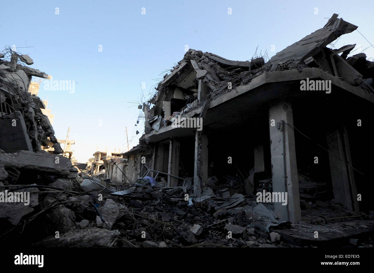 Kobane, Syrien. 21. Dezember 2014. Die kurdischen Verteidiger von Kobane nennen ihre Stadt "Stalingrad". Die Straßen sind Schutt gefüllt, zerbrochene Glas deckt den Boden überall und Scherben aus Metall und Schrapnell bedecken den Boden. Die meisten Häuser sind auf ihren Rahmen reduziert und nicht explodierte Bomben füllen die Straßen. In dieser zerstörten Stadt müssen die Überlebenden mit Handfeuerwaffen, Raketen, Sprengstoff und extrem heftigen alliierten Luftangriffen befassen. Über eine bewegen muss durchlaufen Löcher klopfte in Wänden zwischen Gebäuden oder unter Bettdecke aufgereiht über Freiflächen, die Ansicht des Scharfschützen zu behindern. In den Trümmern kleine ich Stockfoto