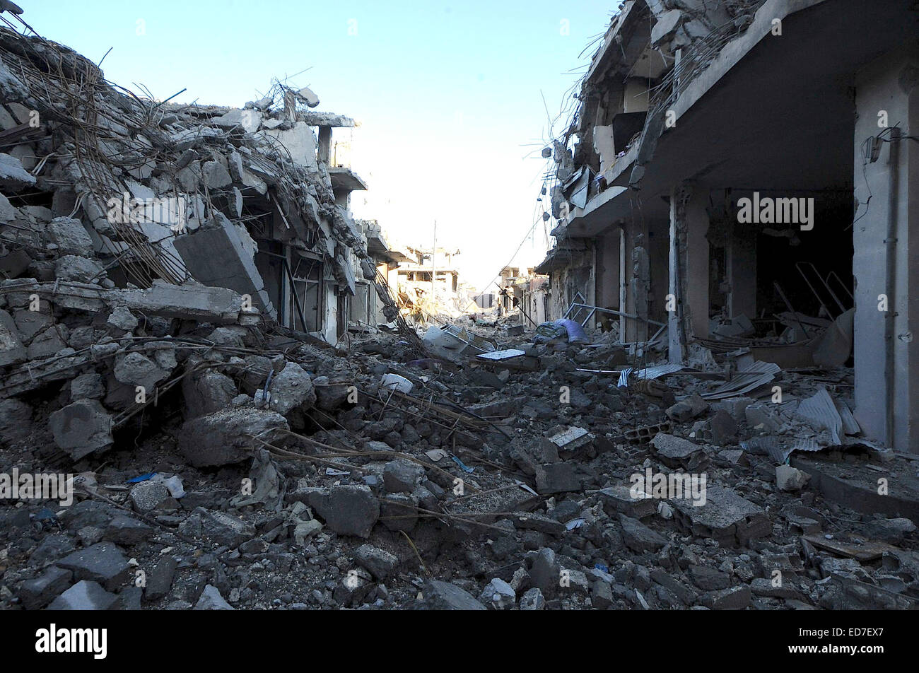 Kobane, Syrien. 21. Dezember 2014. Die kurdischen Verteidiger von Kobane nennen ihre Stadt "Stalingrad". Die Straßen sind Schutt gefüllt, zerbrochene Glas deckt den Boden überall und Scherben aus Metall und Schrapnell bedecken den Boden. Die meisten Häuser sind auf ihren Rahmen reduziert und nicht explodierte Bomben füllen die Straßen. In dieser zerstörten Stadt müssen die Überlebenden mit Handfeuerwaffen, Raketen, Sprengstoff und extrem heftigen alliierten Luftangriffen befassen. Über eine bewegen muss durchlaufen Löcher klopfte in Wänden zwischen Gebäuden oder unter Bettdecke aufgereiht über Freiflächen, die Ansicht des Scharfschützen zu behindern. In den Trümmern kleine ich Stockfoto