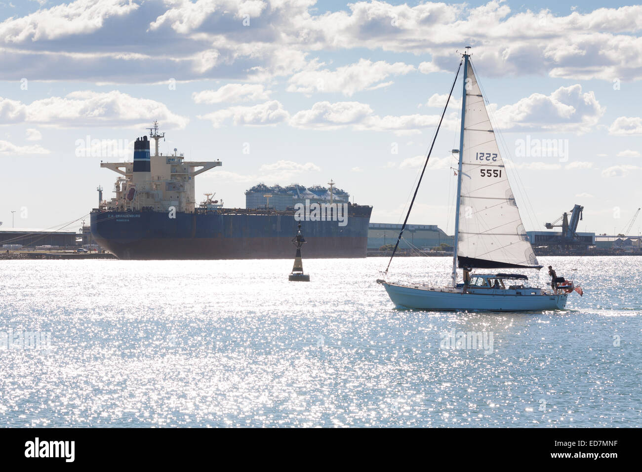 Yacht segelt am Bulk Carrier vorbei, der Kohle für den Export im Hafen von Newcastle NSW Australia lädt. Stockfoto