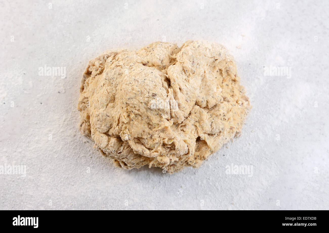 Grobe Ball aus rohen gemischten Samen Brotteig auf einer bemehlten Arbeitsfläche vor dem Kneten Stockfoto