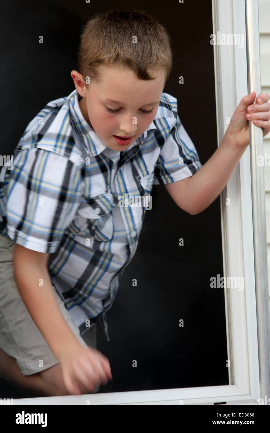 Ein kleiner Junge verlassen das Fenster von einem rauchigen Raum auf einem überleben lebendig Anhänger Stockfoto