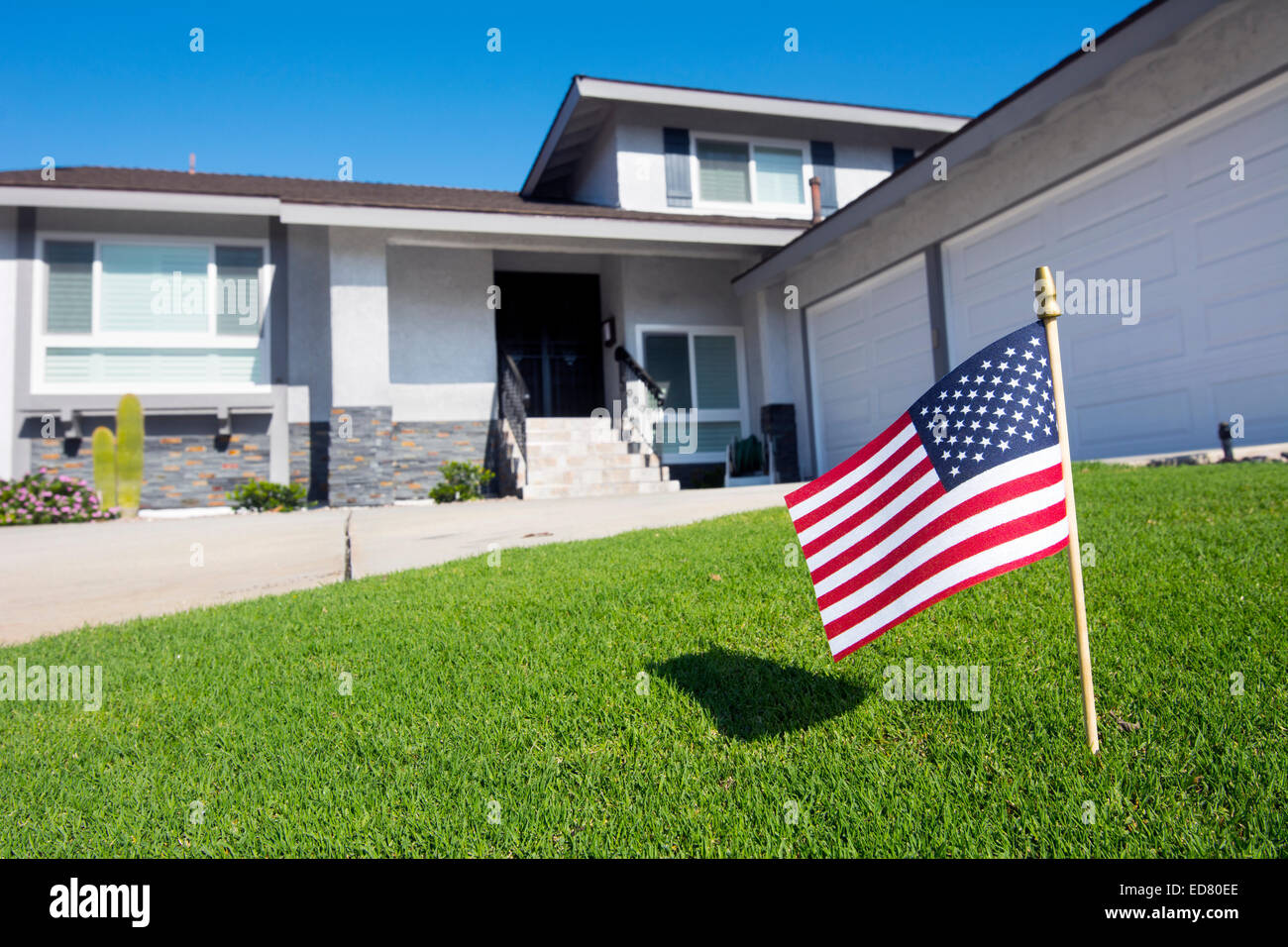 Ein Eigenheimbesitzer zeigt eine amerikanische Flagge in ihrem Garten bei einem patriotischen Urlaub Stockfoto