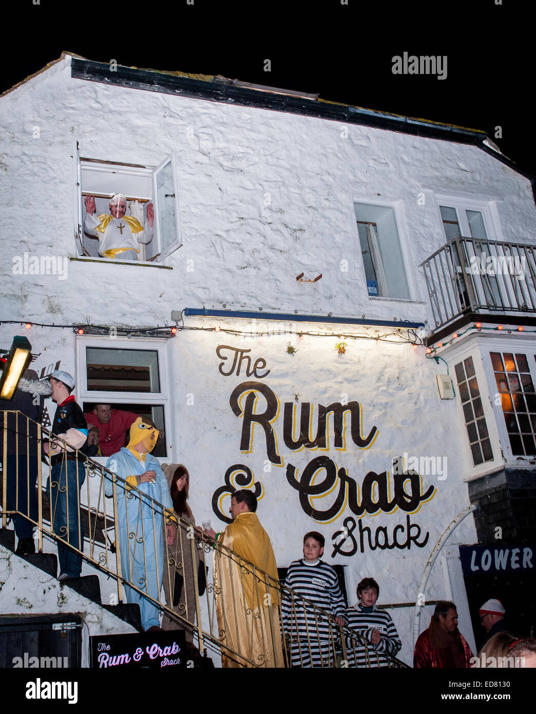 Nachtschwärmer Queueing, eine Bar einzugeben, wie der Papst sie aus dem Fenster begrüßt!  Silvester feiern in St. Ives in Cornwall, Großbritannien am 31. Dezember 2014. Jedes Jahr trägt die ganze Stadt Kostüm Stockfoto