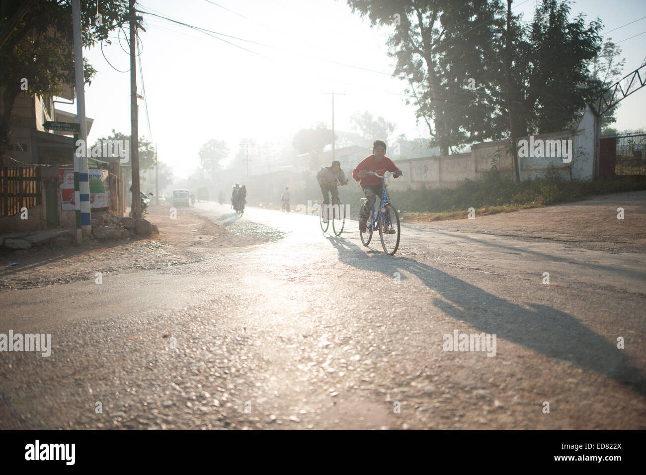 Kinder, die Radfahren in den frühen Morgen Schein der Sonne, Loikaw Stockfoto