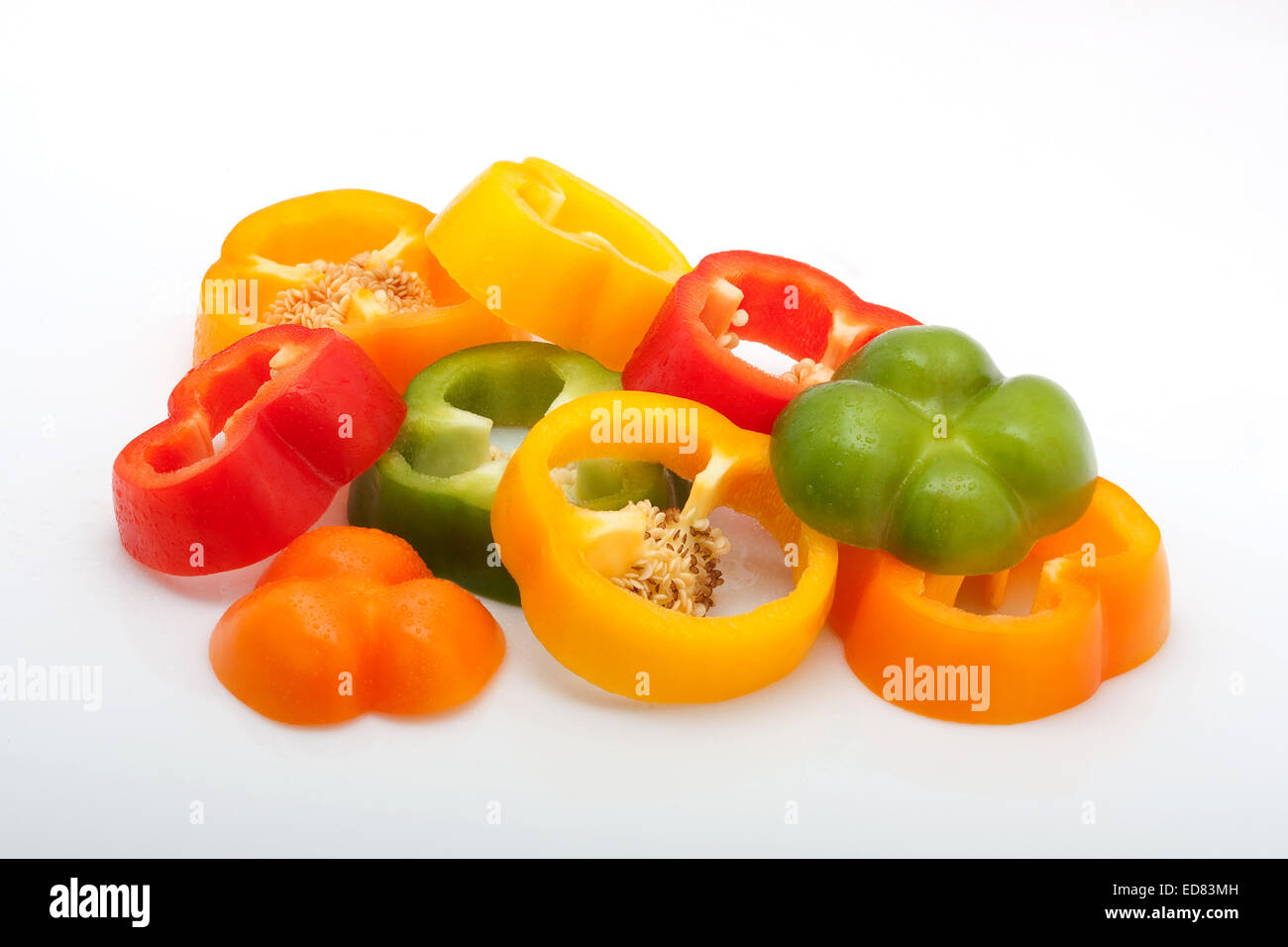 frisch geschnittene rote, grüne, gelbe und orange Paprika mit Wassertropfen isoliert auf weißem Hintergrund Stockfoto