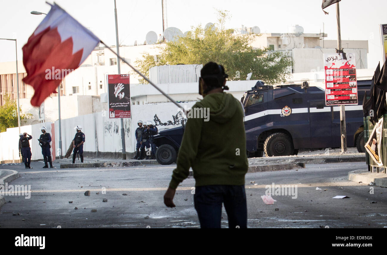 Ein Demonstrant "Wellenlinien" Bahrain Fahne vor die bahrainische Sicherheitskräfte. Bahrainische Sicherheitskräfte unterdrücken Demonstranten fordern Freiheit für Scheich Ali Salman, nachdem sie Scheich Ali Salman, Leiter der Al-Wefaq Gesellschaft - den größten Widerstand Gesellschaften in Bahrain - mehr als drei Tage lang festgehalten. © Hussain Albahrani/Pacific Press/Alamy Live-Nachrichten Stockfoto