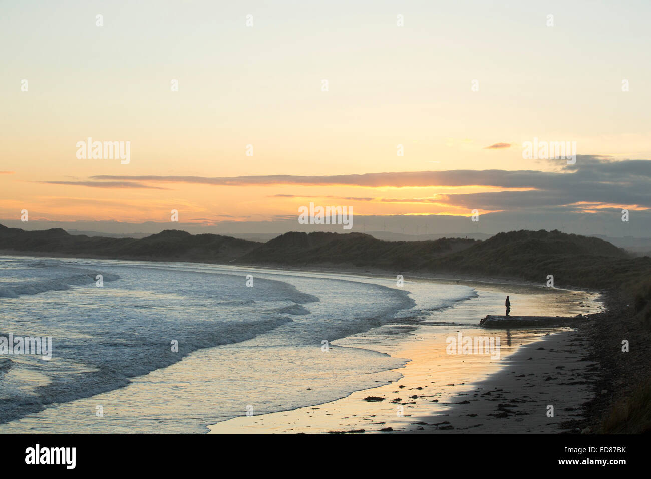 Ein Mann am Beadnell Strand bei Sonnenuntergang, Northumberland, UK. Stockfoto