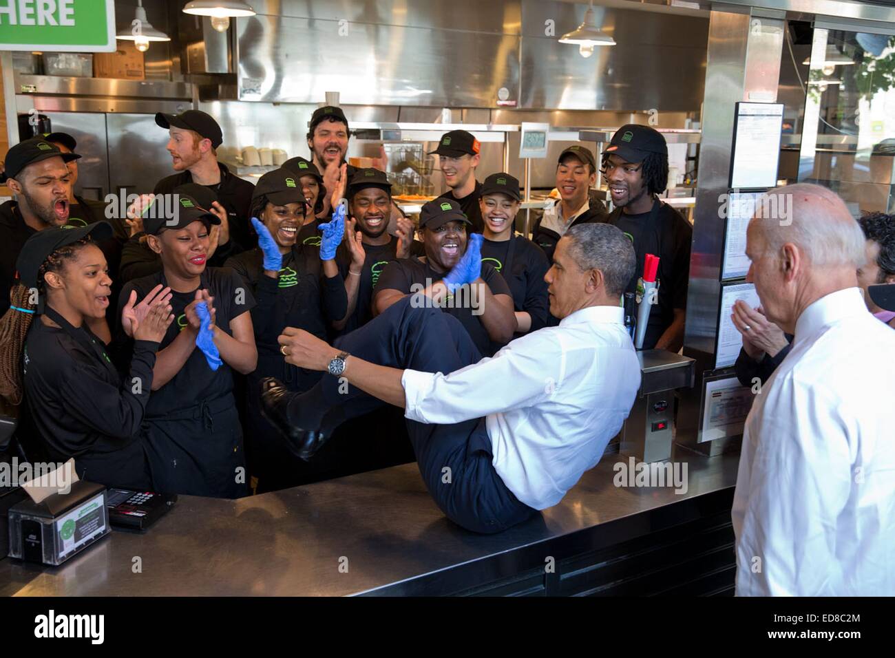 US-Präsident Barack Obama gleitet über den Ladentisch zu posieren für ein Gruppenfoto mit Mitarbeitern im Shake Shack Restaurant nach dem Mittagessen mit Vizepräsident Biden Mai 16, 2014 in Washington, DC. Stockfoto