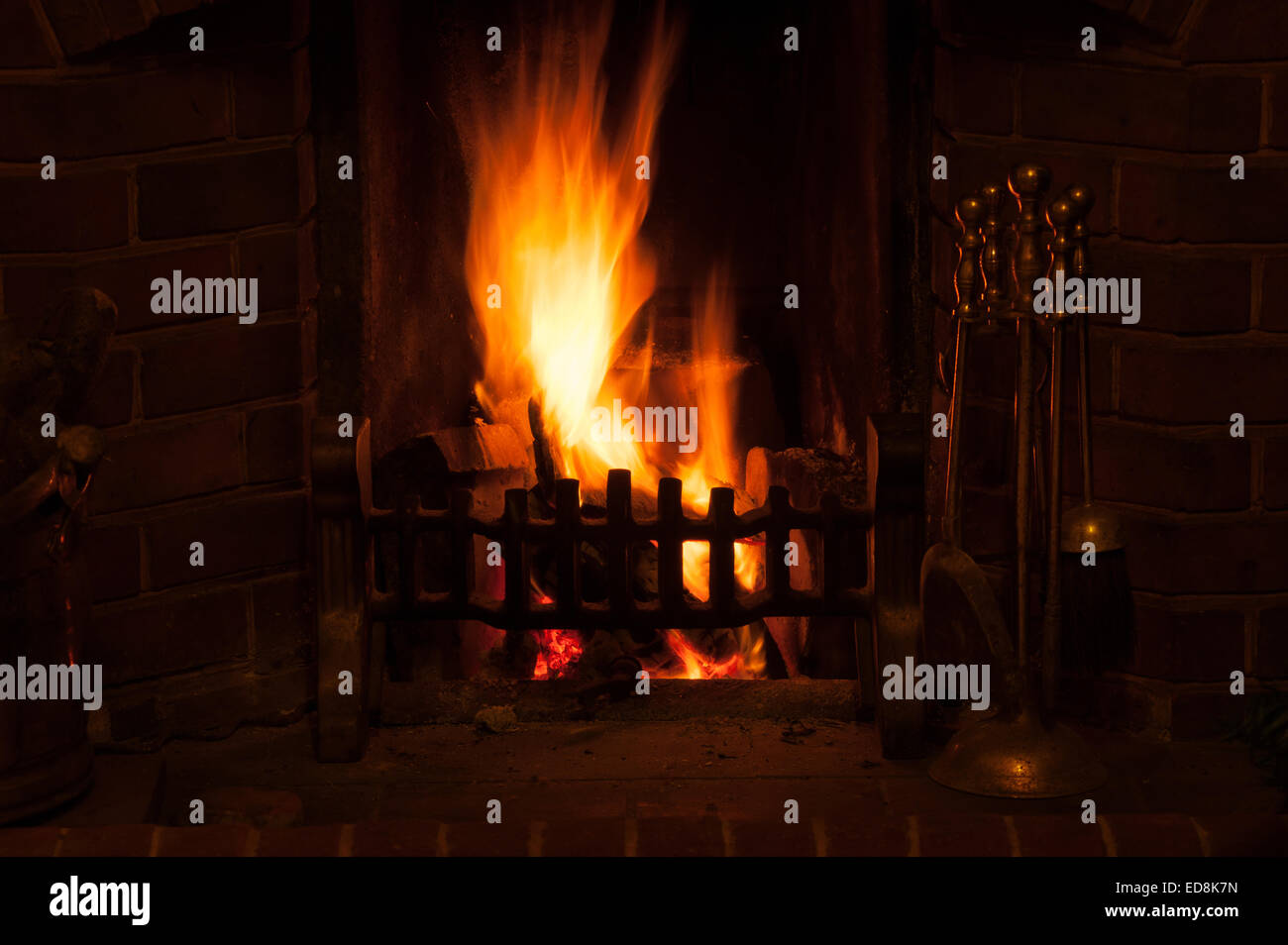 Herzlich Leuchten einer traditionellen Winter-Szene wie am offene Feuer in einem Haus leuchtende Licht strahlt, wie Holz Glut und Kohle heiß verbrennen Stockfoto