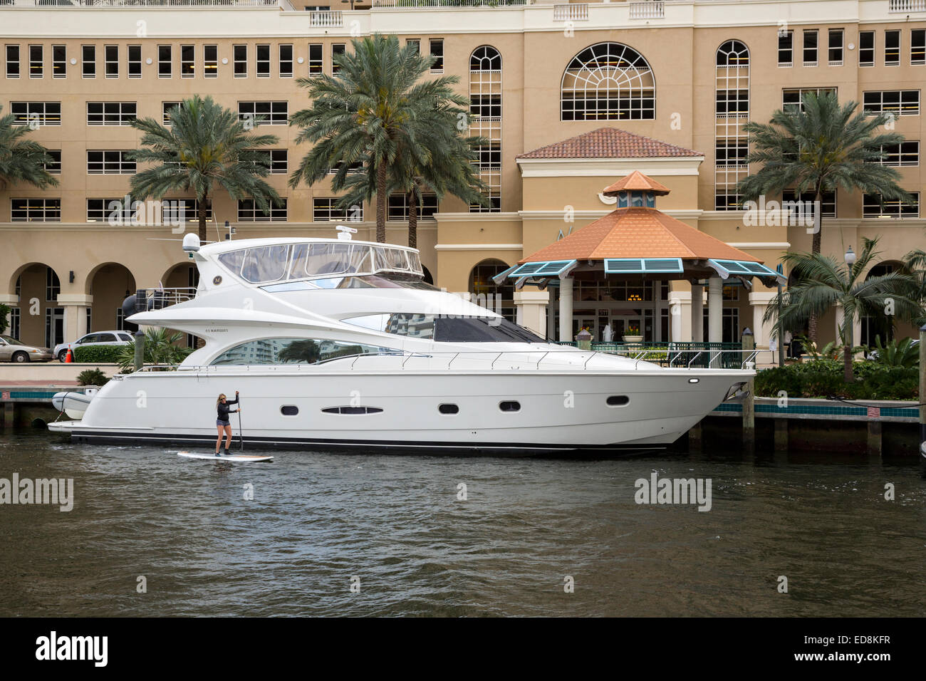 Ft. Lauderdale, Florida.  Junge Frau paddelt ihr Surf Board letzten an teuren Boot vor Nu River Landing Eigentumswohnung. Stockfoto