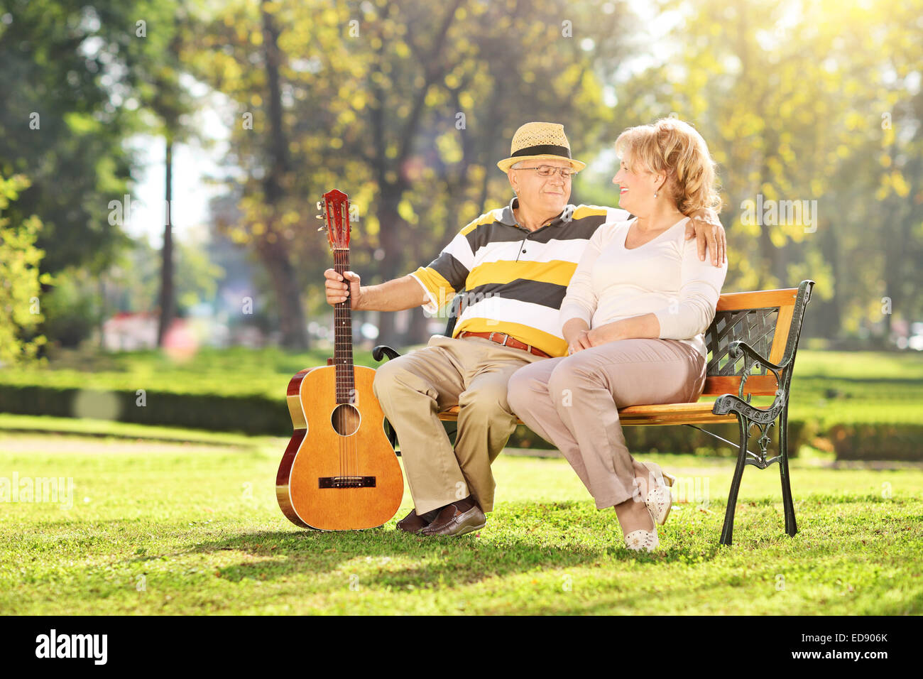 Reifer Mann mit seiner Frau im Park sitzen und halten eine Gitarre Stockfoto