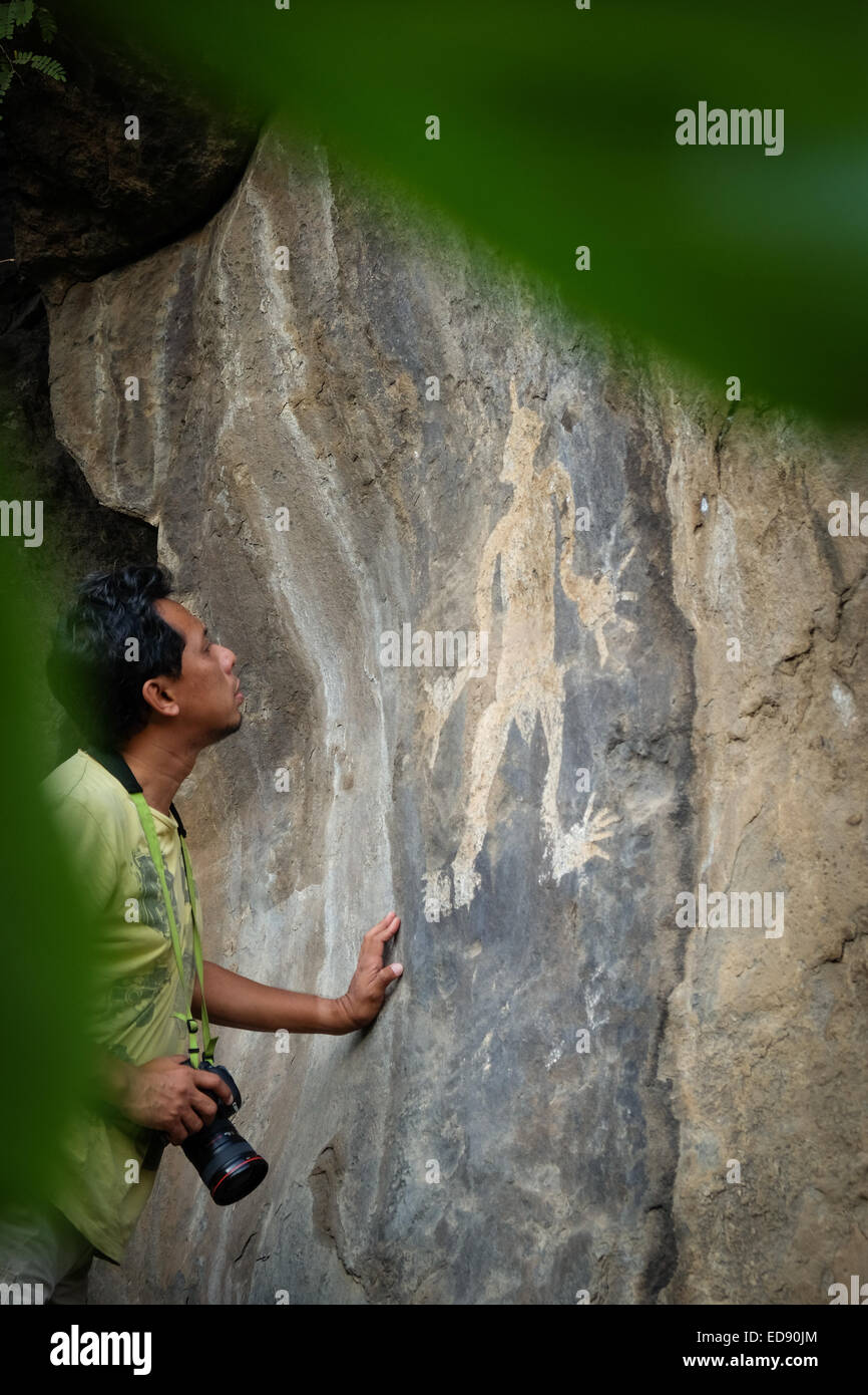 Des Syafrizal, ein Fotograf, achtet auf ein Felsgemälde auf einer Klippe im Dorf Lamagute, Lembata, East Nusa Tenggara, Indonesien. Stockfoto