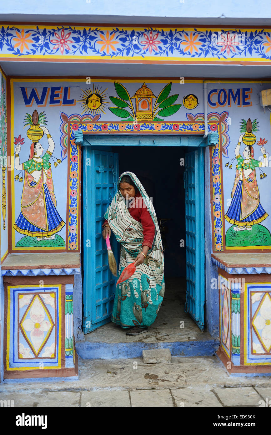 Indien, Rajasthan, Mewar Region, Bundi Dorf dekoriert Tür eines traditionellen Hauses, Frau fegt der Haustür Stockfoto