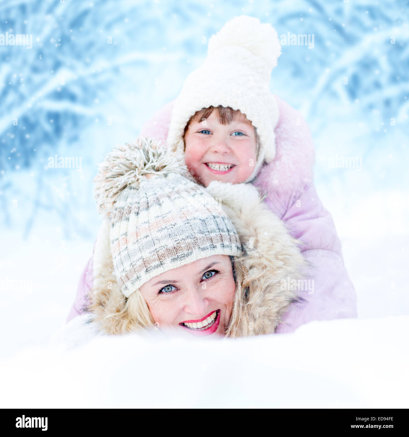 Glückliche Mutter und Kind Lügen in Schneewehe im freien Stockfoto