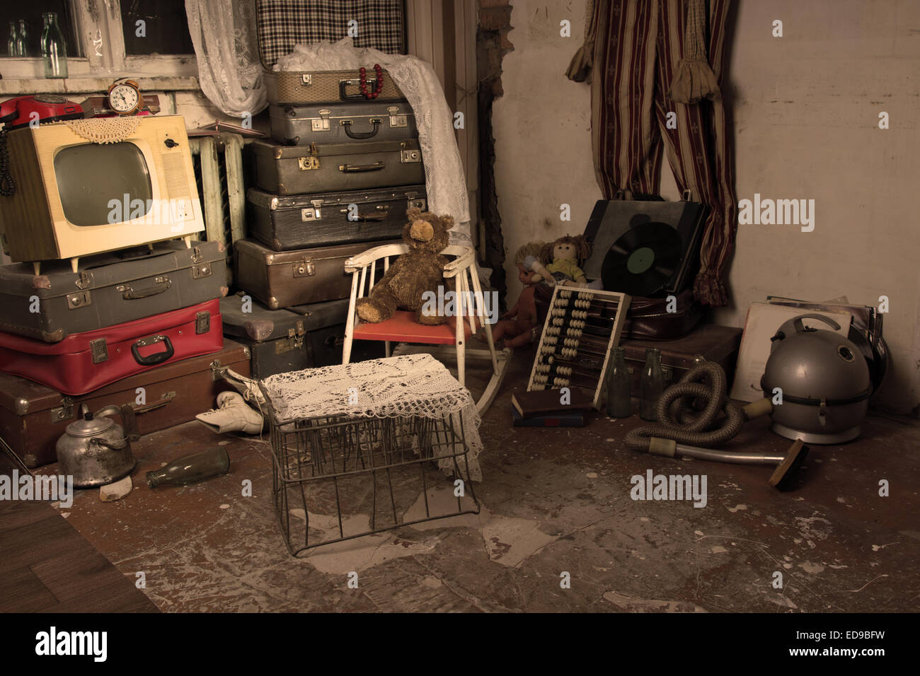 Sortierte ausrangierten alten Elemente in ein altes Zimmer mit Gepäck, Käfig, Fernsehen und andere Gegenstände. Stockfoto