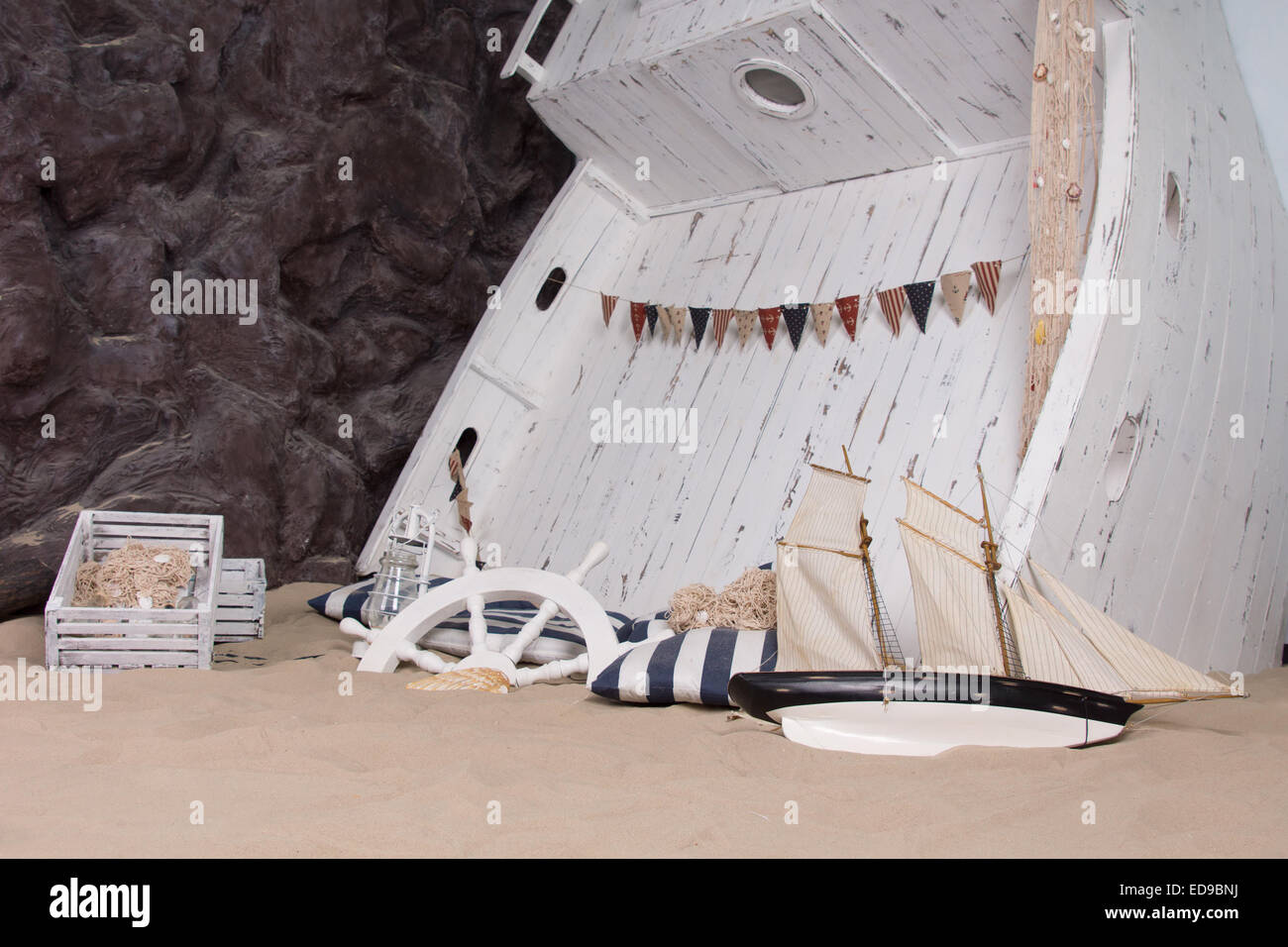 Marine oder nautischen Themen Stillleben darstellt ein Wrack mit einem Holzboot hochkant in den Sand mit einem Schiffe Rad, Laterne, Stockfoto