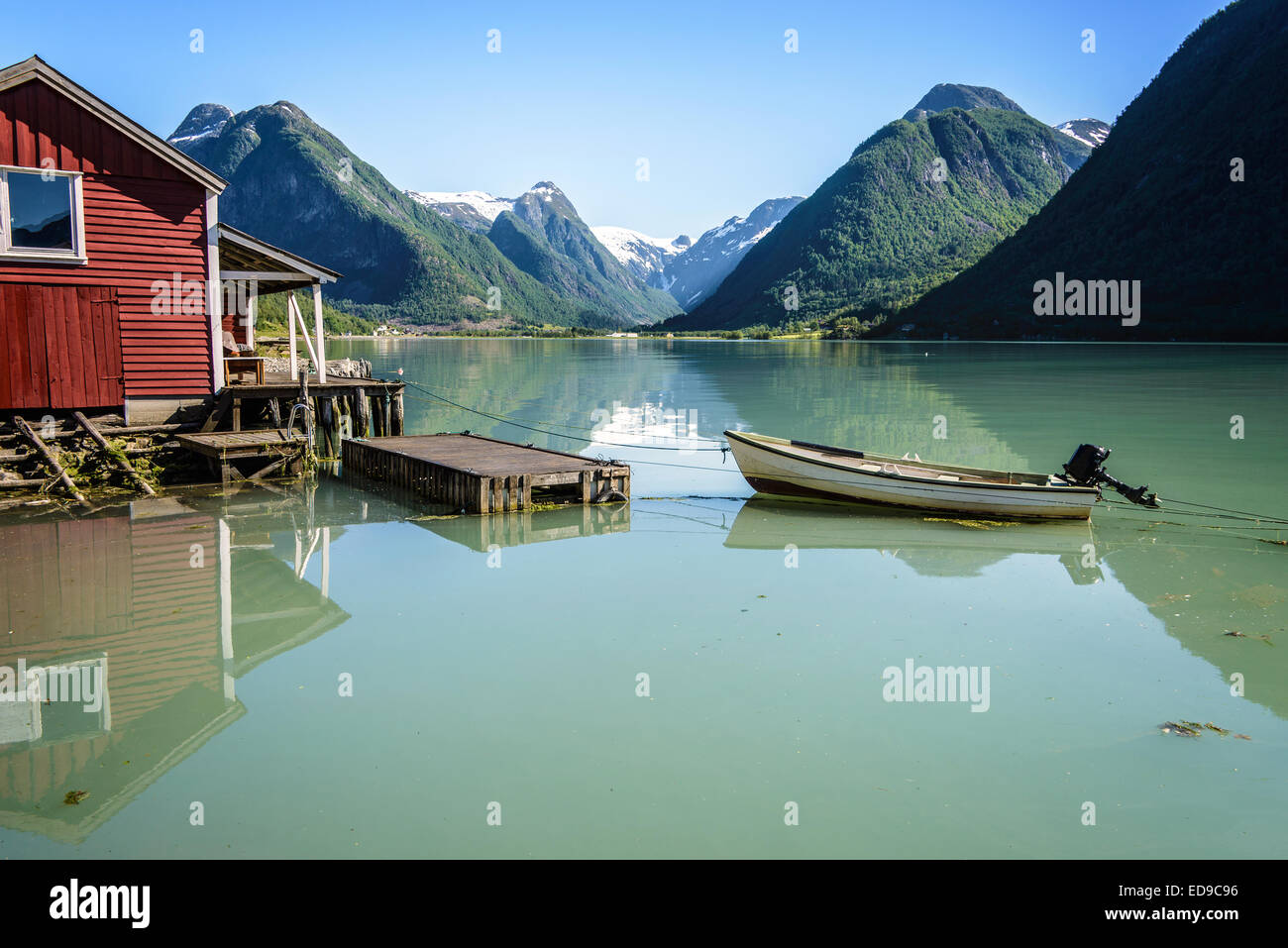 Reflexion eines Bootes, einen Steg, eine rote Bootshaus und Berge im ruhigen Wasser des Rv5, in der Nähe von Sognefjord in Norwegen. Stockfoto