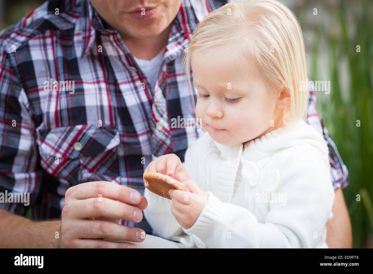 Entzückende kleine Mädchen einen Cookie mit Papa draußen essen. Stockfoto
