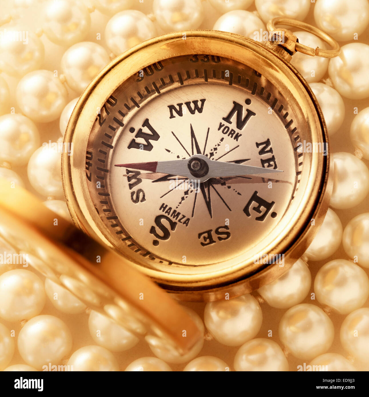Goldene Kompass auf Perlenkette als Hintergrund Stockfoto