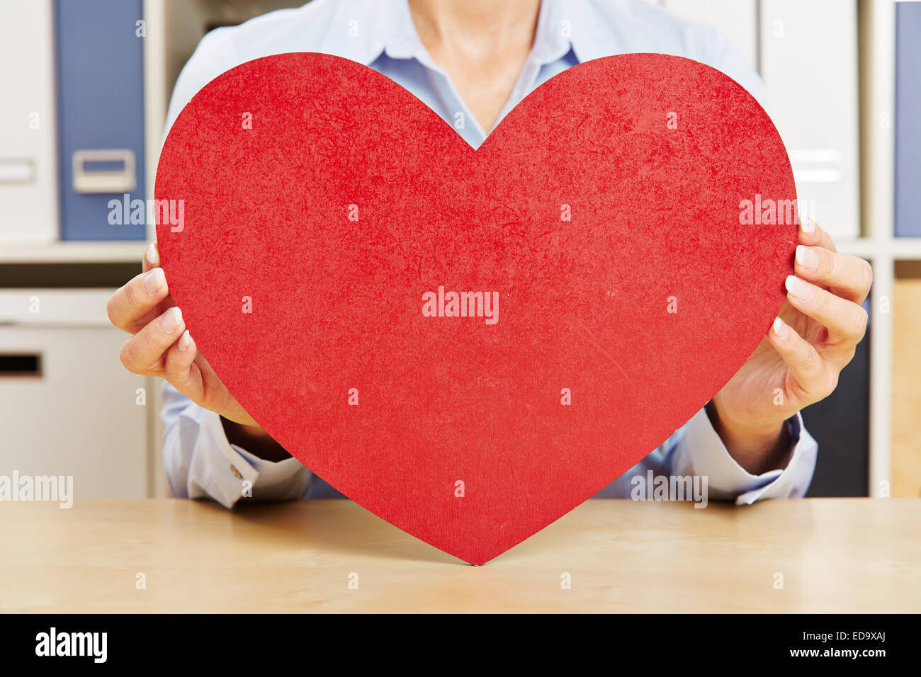 Hände einer Frau mit großen roten Herz auf einem Schreibtisch Stockfoto
