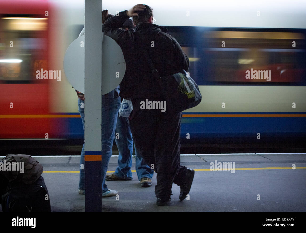 Mann warten auf ein Zug im Southampton Central Bahnhof mit einem Zug gehen vorbei gezeigt mit Motion blur. Stockfoto