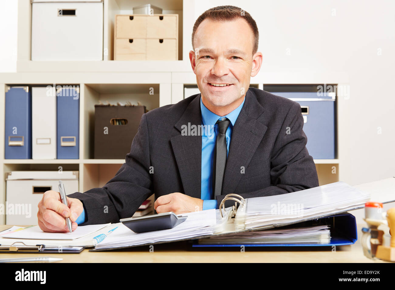 Finanzen-Schreiber sitzt an seinem Schreibtisch mit Dateien und einen Taschenrechner Stockfoto
