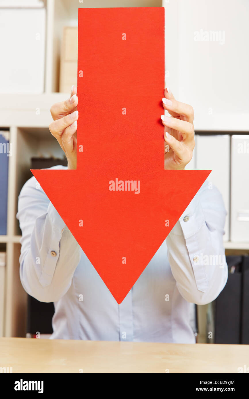 Große rote Pfeil nach unten in einem Büro wird von Händen gehalten Stockfoto