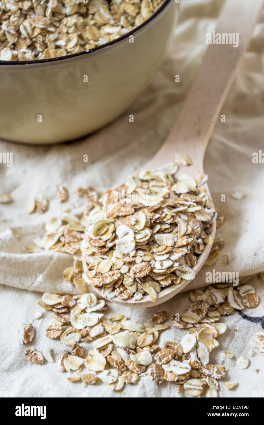 Haferflocken in einem Holzlöffel und eine Schüssel Müsli Stockfoto