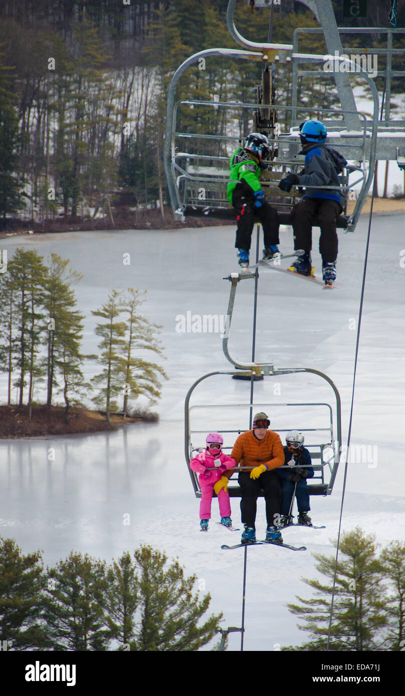 Skifahrer und Snowboarder steigen an die Spitze der Madison, New Hampshire König Kiefer Skipiste über einen Sessellift. Stockfoto