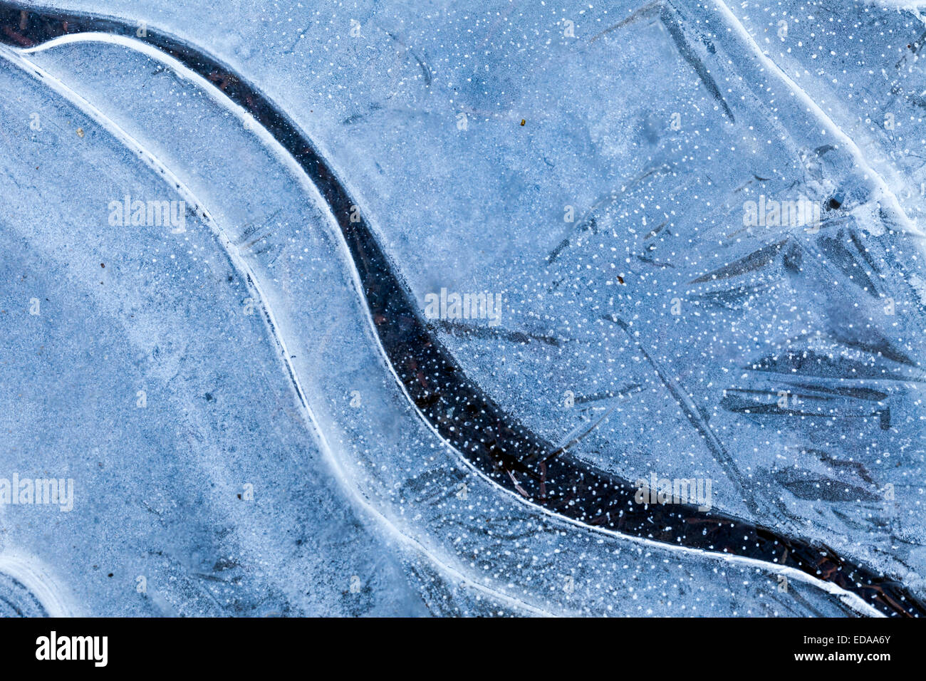 Gebogene Fraktur mit Kristallwachstum auf eine gefrorene Pfütze Stockfoto