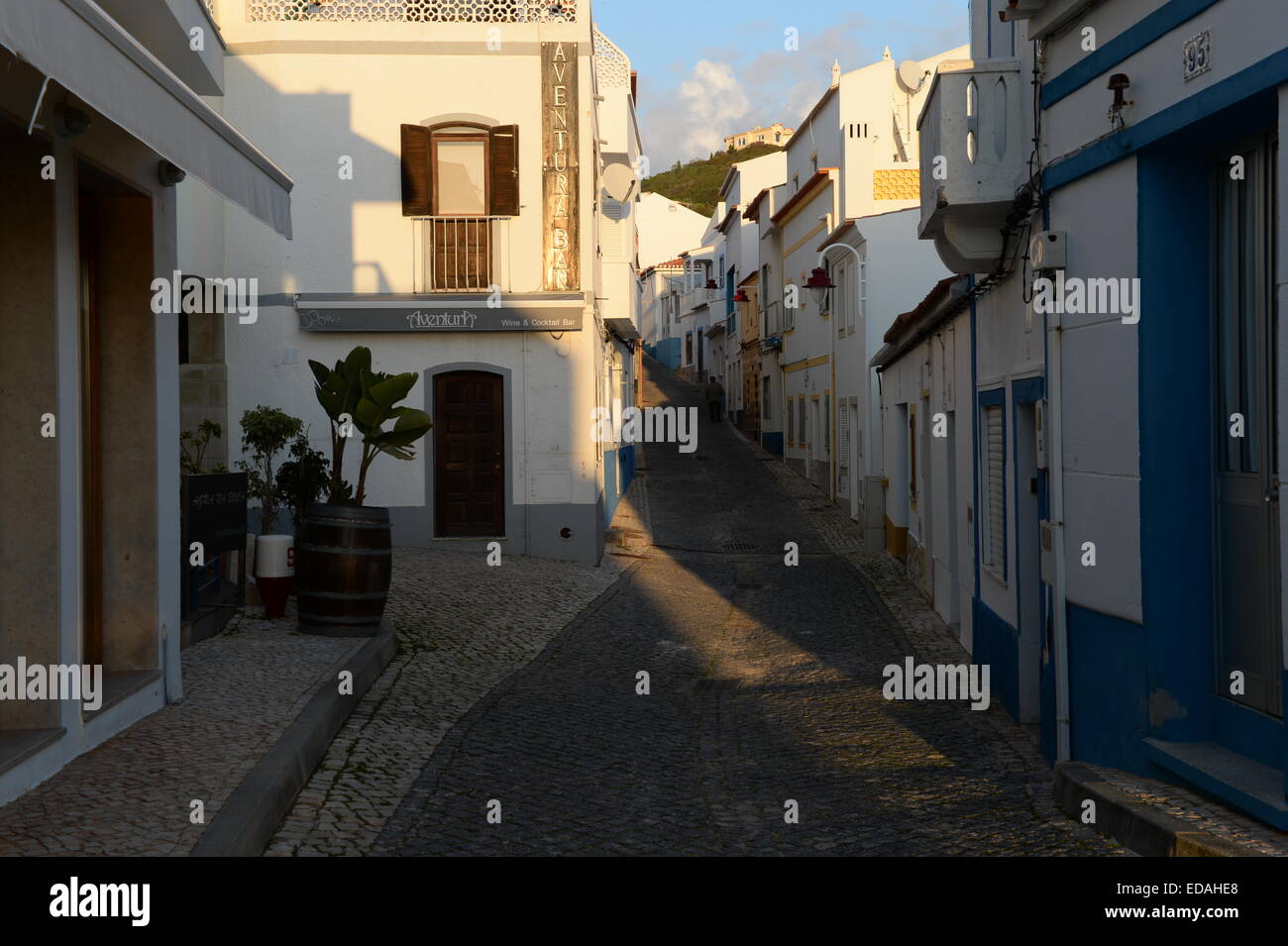 Eine einzelne Figur auf Rue de Pescadores, eine schmale gepflasterte Straße in Salema, das seinen ursprünglichen Charme bewahrt hat. Stockfoto