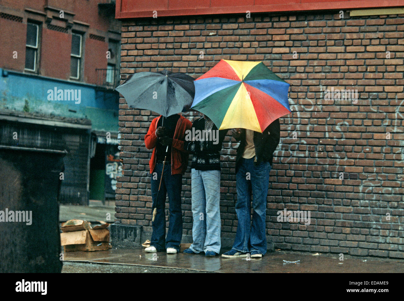 USA, HARLEM, NEW YORK CITY - APRIL 1978. Harlem Bewohnern verstecken ihre Gesichter mit Sonnenschirmen, New York City. Stockfoto