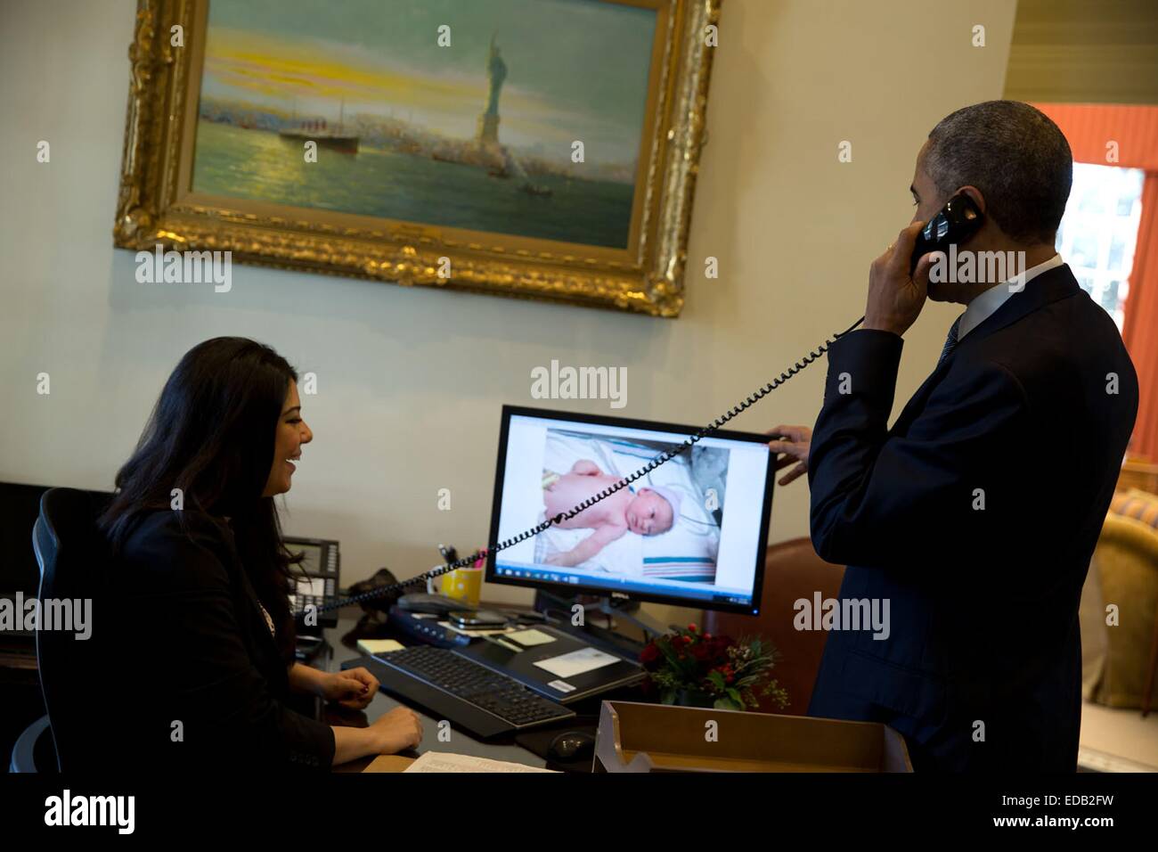 US-Präsident Barack Obama gratuliert stellvertretender National Security Advisor Ben Rhodes telefonisch Ferial Govashiri zeigt ein Foto auf ihrem Computer von Bens neugeborenen Sohn für den Präsidenten 11. Dezember 2014 in Washington, DC. Stockfoto