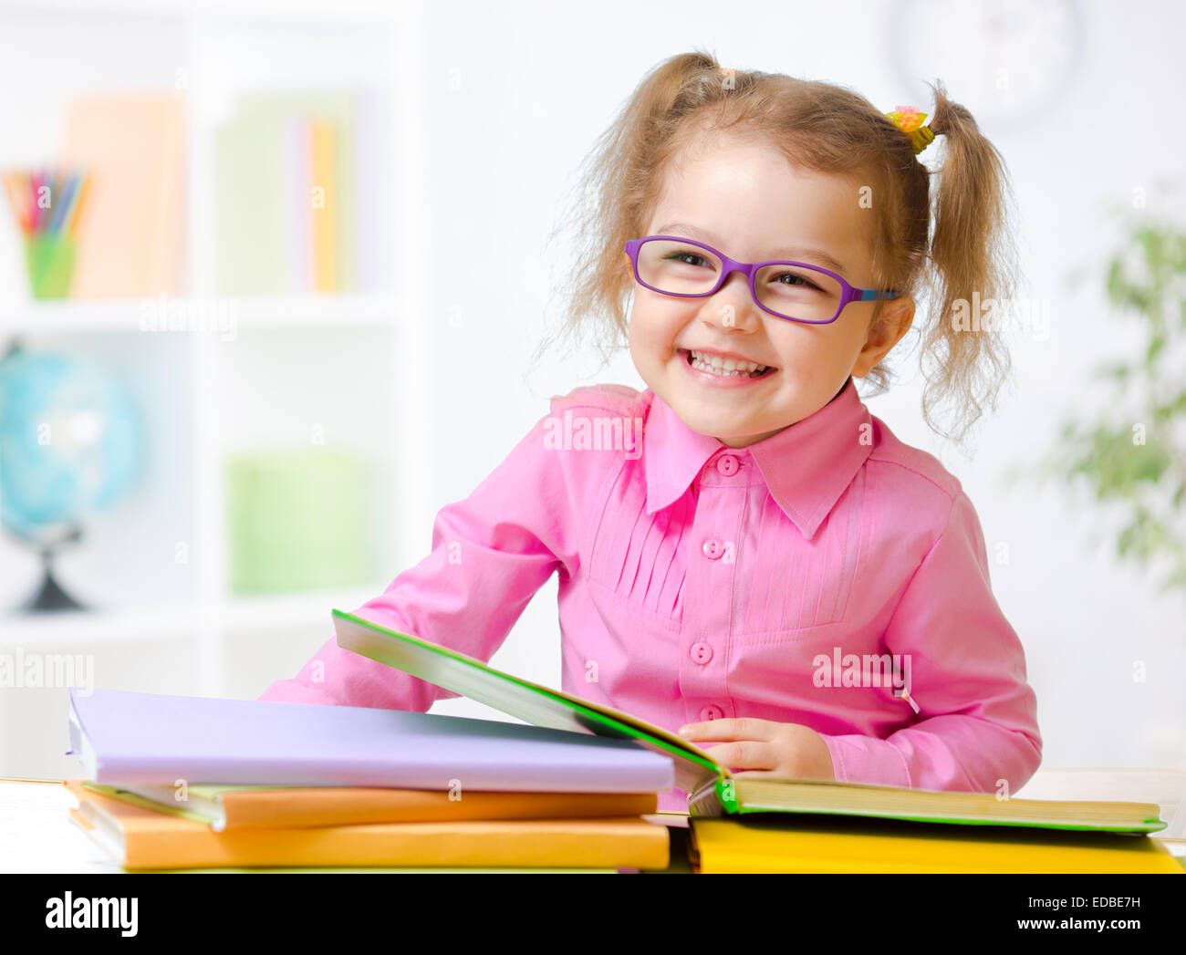 Glückliches Kind Mädchen in Gläsern Lesen von Büchern im Zimmer Stockfoto