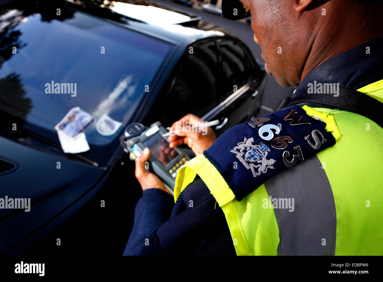 Ein Traffic Warden erlässt ein Parkticket Stockfoto