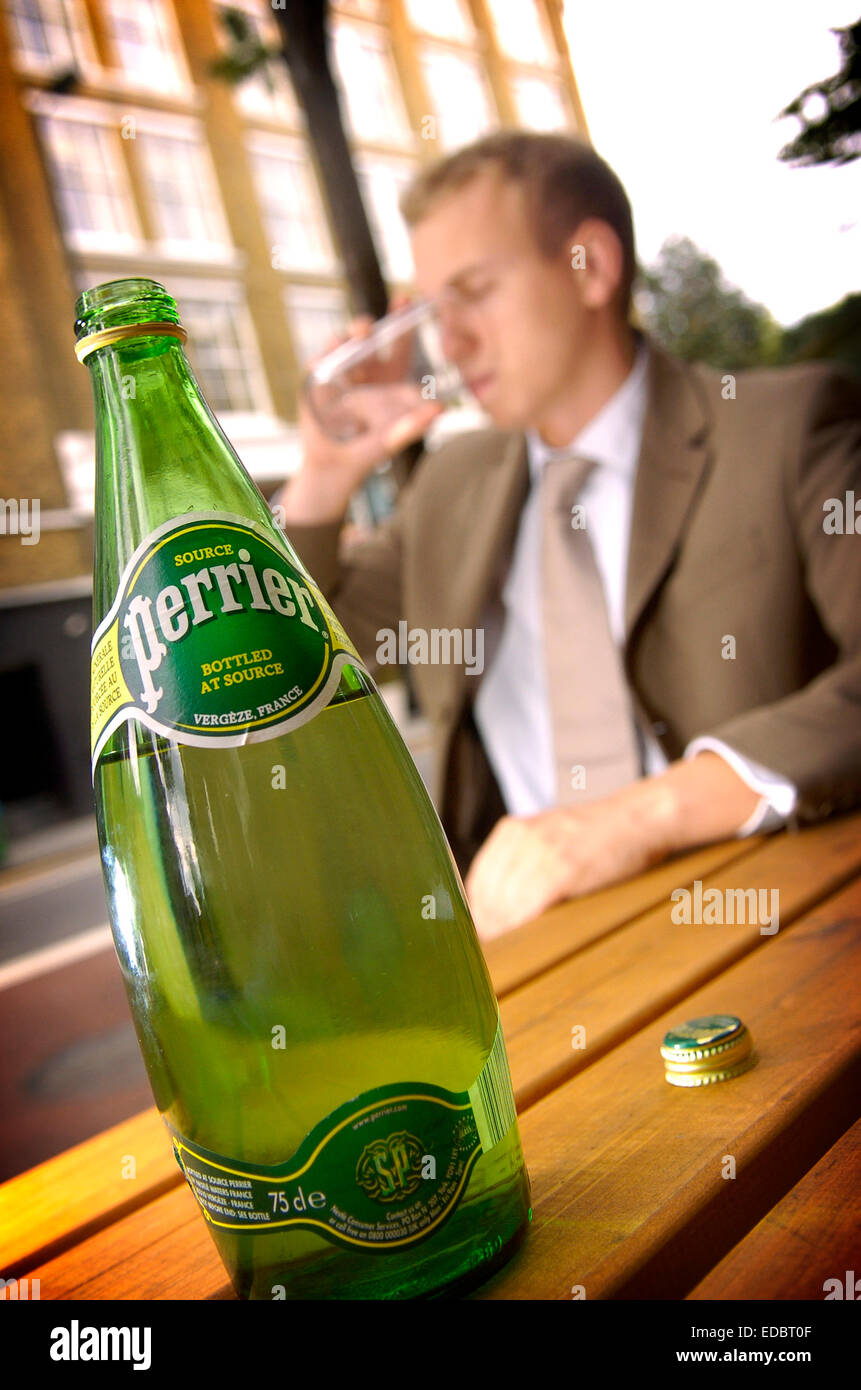 ein Mann genießt ein Glas Mineralwasser Perrier Wasser; eine Marke von Nestlé Waters. Stockfoto