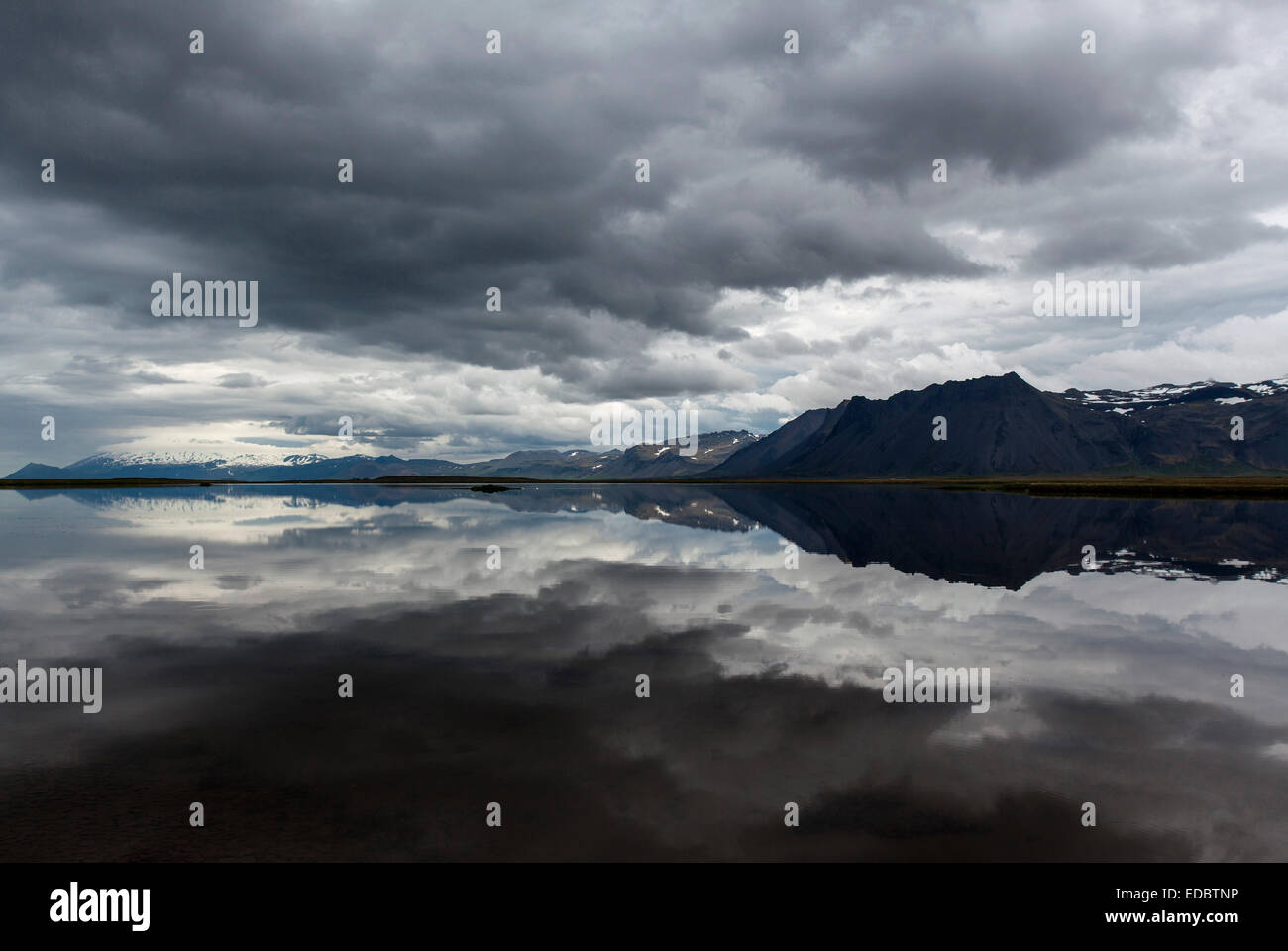 See, Berge an derRückseite, dunkle Wolken spiegeln sich im Wasser, in der Nähe von Gardar Snaefellsnes Halbinsel, Island Stockfoto