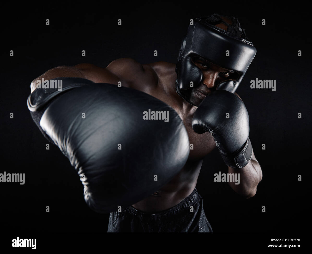 Porträt des jungen männlichen Praktizierenden Boxen auf schwarzem Hintergrund. Afrikanische männlichen Boxer werfen einen Schlag vor. Junge Sportler Stockfoto