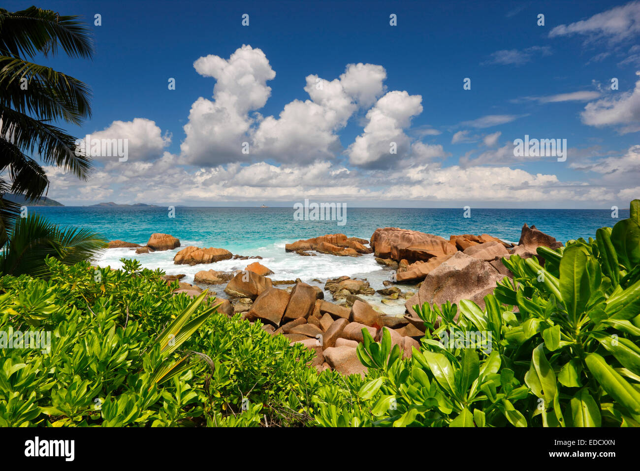 Steiniger Strand auf den Seychellen mit viel Grün und schönen bewölkten Himmel im Hintergrund Stockfoto