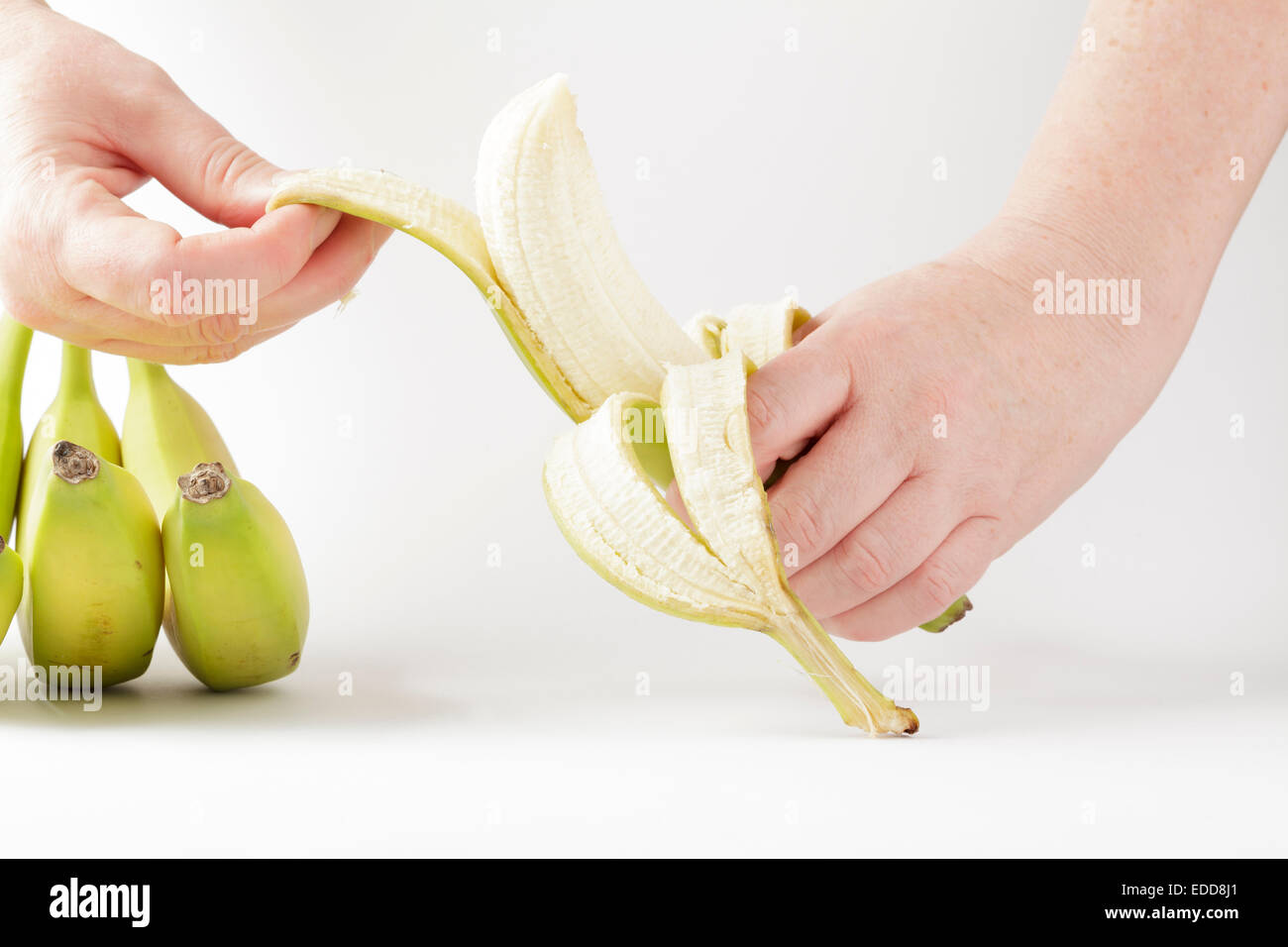Hände, die eine Banane schälen Stockfoto
