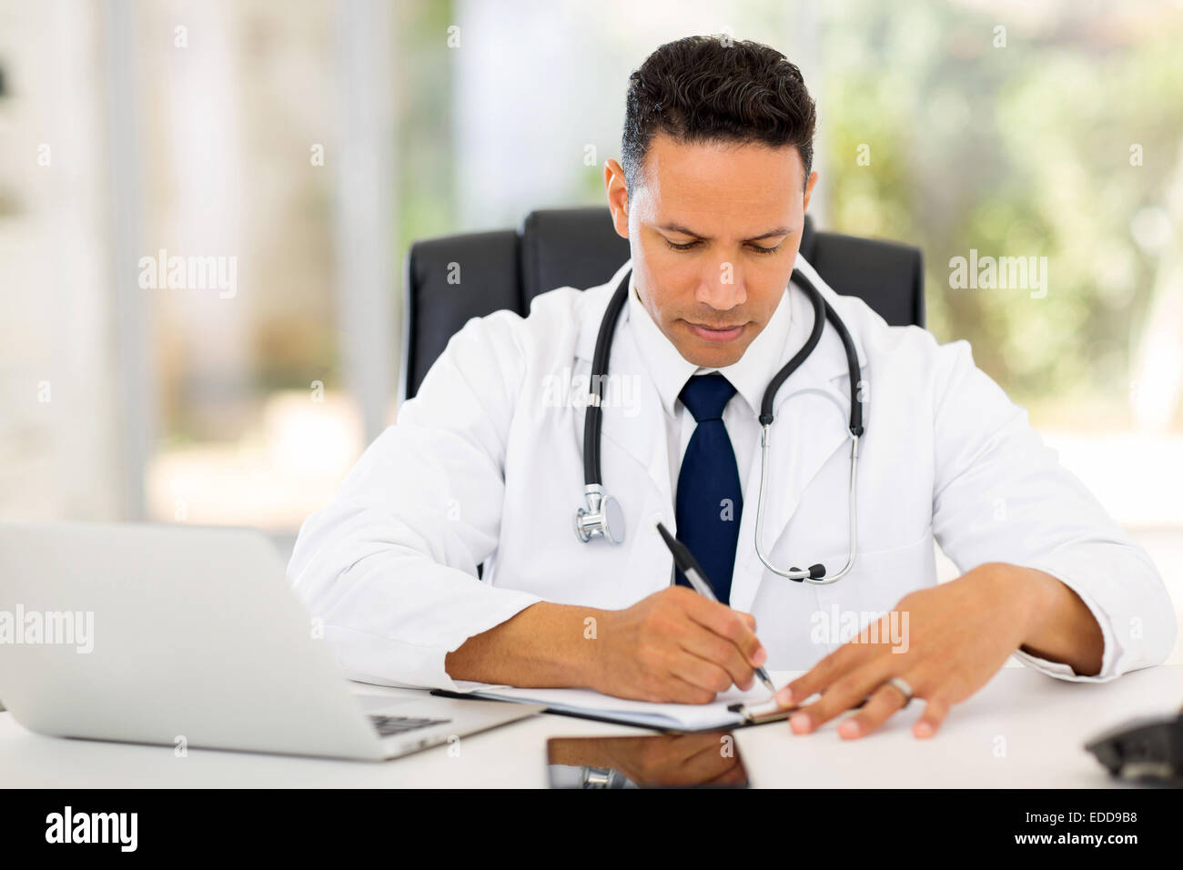 männlichen Arzt schreiben von Berichten in seinem Büro Stockfoto